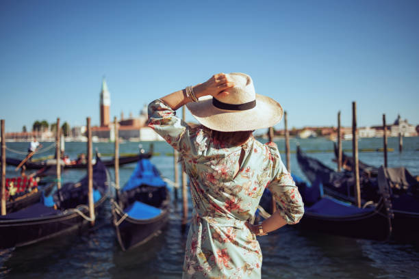 Seen from behind stylish traveller woman in floral dress stock photo