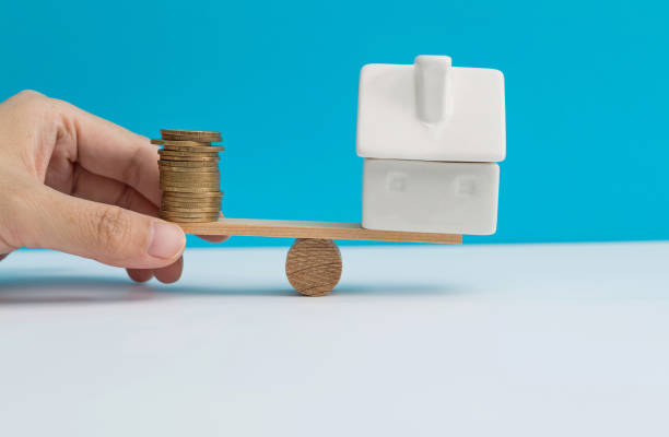 Seesaw with house model and coins stock photo