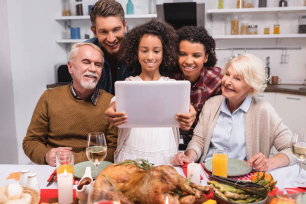şükran kutlamaları sırasında ebeveynlerin yanında dijital tablet tutan afrikalı-amerikalı kız seçici odak - happy thanksgiving stok fotoğraflar ve resimler