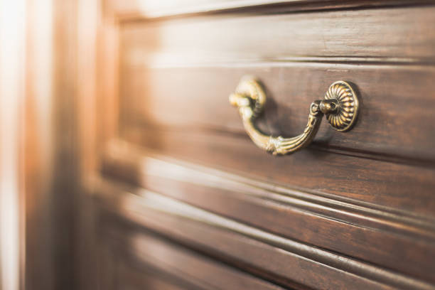 Selective focus of Brass Handle on Antique Cabinet with warm light stock photo
