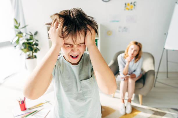 selective focus of irritated kid with dyslexia shouting and holding head selective focus of irritated kid with dyslexia shouting and holding head Fingers in Ears stock pictures, royalty-free photos & images