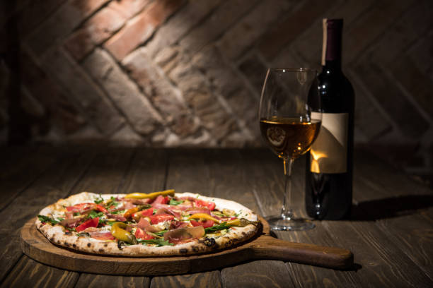 selective focus of italian pizza, bottle and glass of wine on wooden tabletop - pizza table imagens e fotografias de stock