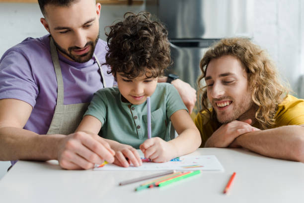 selective focus of mixed race kid drawing near happy homosexual parents selective focus of mixed race kid drawing near happy homosexual parents gay person stock pictures, royalty-free photos & images