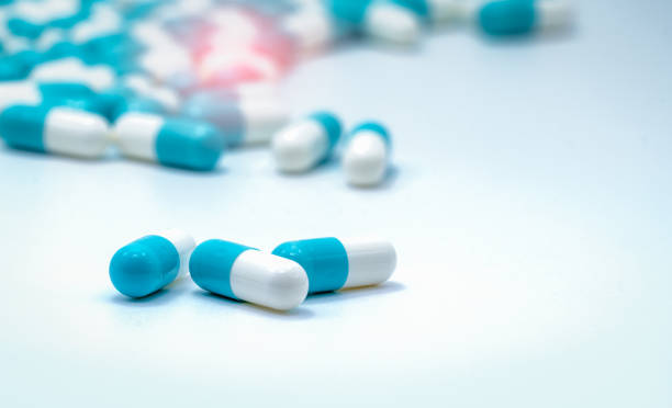 Selective focus on blue and white capsules pill spread on white background. Global healthcare. Antibiotics drug resistance. Antimicrobial capsule pills. Pharmaceutical industry. Pharmacy background. Selective focus on blue and white capsules pill spread on white background. Global healthcare. Antibiotics drug resistance. Antimicrobial capsule pills. Pharmaceutical industry. Pharmacy background. pics for amoxicillin stock pictures, royalty-free photos & images