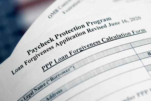 selective focus photo of paycheck protection program loan forgiveness application form revised, on a background of United States flag. paycheck protection program new round. stock photo