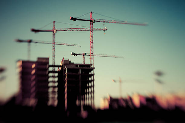 Selective focus silhouettes of construction cranes stock photo
