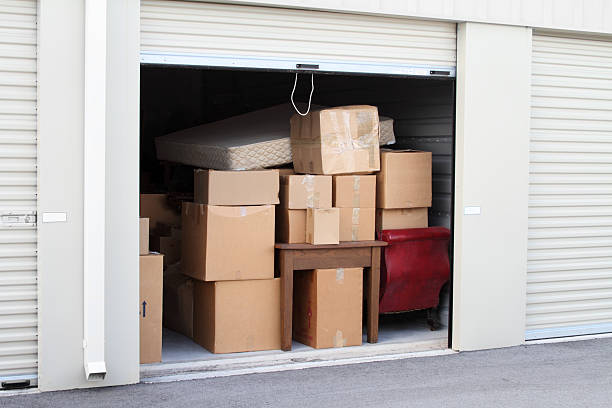 Self storage warehouse building with an open unit. Warehouse building with self storage units. Self storage facility. Roll up door open with boxes and furniture in doorway.  self storage stock pictures, royalty-free photos & images