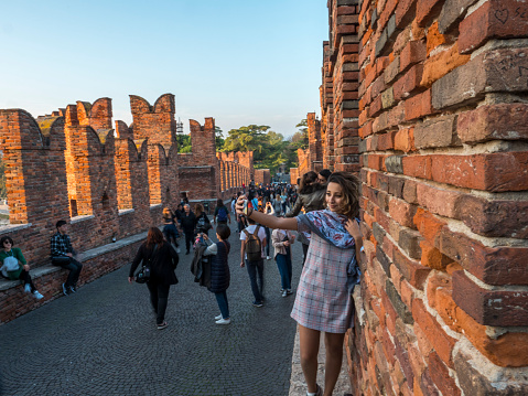 Dozens of tourists visit and take photos and selfies on the  Castel vecchio bridge, one of the symbols of Verona, Italy