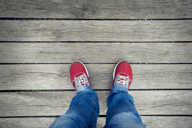 selfie di sneakers rosse su gambe su sfondo legnoso. - shoes top view foto e immagini stock