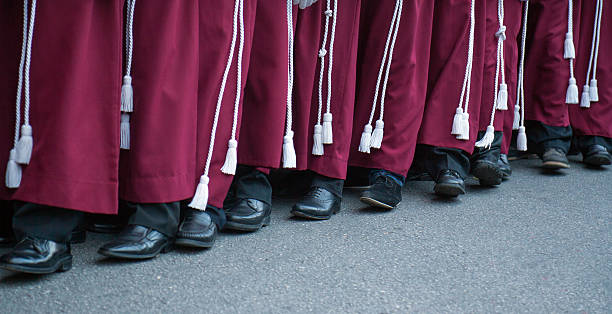 Semana Santa in Malaga: procession of Rescate brotherhood Close up of a row of feet belonging to men dressed in traditional red robes of the Rescate brotherhood in Malaga, with black shoes and white cords, who carry the float of Jezus Christ (not visible) in the Easter procession on holy Tuesday . holy week stock pictures, royalty-free photos & images