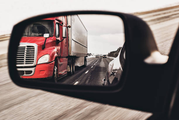 Semi Truck in Mirror Semi truck in the side view mirror of a car. semi truck back stock pictures, royalty-free photos & images