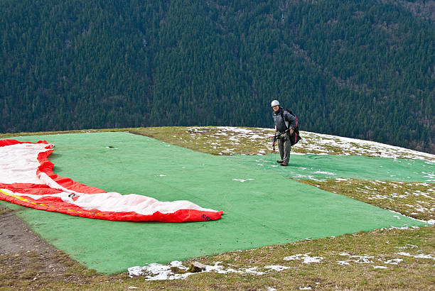 Paraglider Getting Ready to Take Off Tiger Mountain State Forest, Washington, USA - March 07, 2012: A senior adult paraglider adjusts his equipment before taking off from Poo Poo Point. jeff goulden paragliding stock pictures, royalty-free photos & images