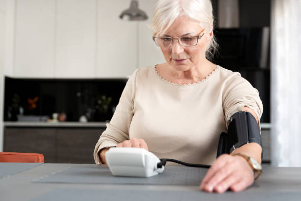 Senior adult woman measuring blood pressure Senior adult woman measuring blood pressure at home blood pressure gauge stock pictures, royalty-free photos & images
