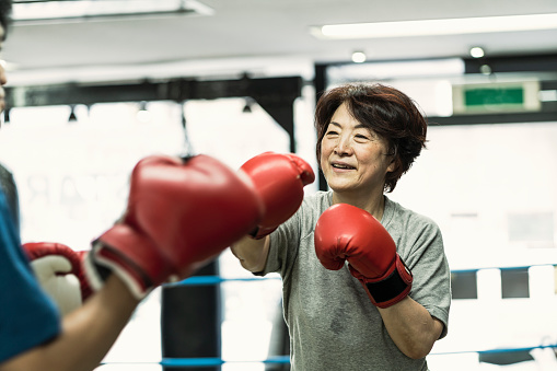 Japanese senior adult women training with male instructor at boxing gym