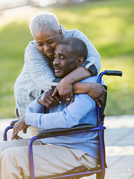 senior african american couple, man in wheelchair - embrace man woman serious stockfoto's en -beelden