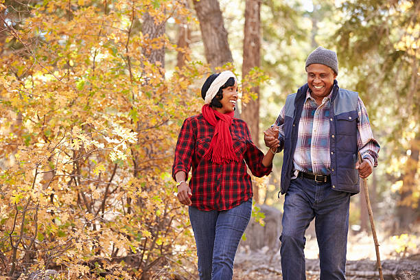 senior afro-americana coppia che cammina attraverso il bosco autunnale - autunno energia foto e immagini stock