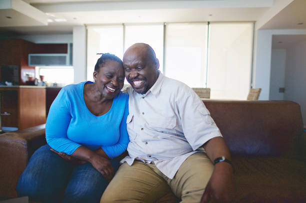 Senior African Couple sitting on a sofa being in love A Senior African Couple sitting on a leather sofa being in love smiling Strand Cape Town South Africa old black couple in love stock pictures, royalty-free photos & images