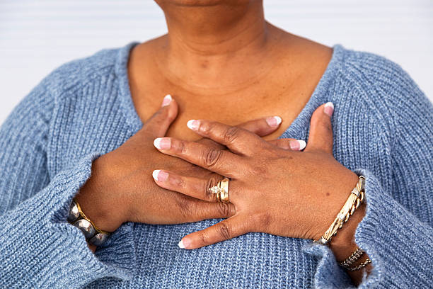 Senior African descent woman clutches chest in pain Senior African descent woman clutches chest in pain. chest pain stock pictures, royalty-free photos & images