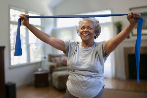 anziana donna afro-americana che si esercita all'interno della casa - aerobica foto e immagini stock