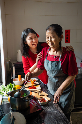 Senior Asian woman and her daughter preparing food  for family reunion dinner on Chinese New Year’s Eve in domestic kitchen