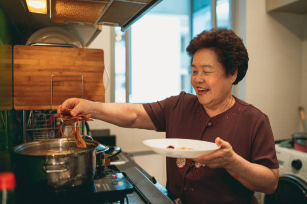 Senior Asian woman preparing Chinese food lotus soup stock photo