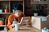 istock Senior Asian woman relaxing at home, shopping online with smartphone, receiving delivered parcels by home delivery service. Online shopping, online banking. Enjoyable customer shopping experience 1347685713