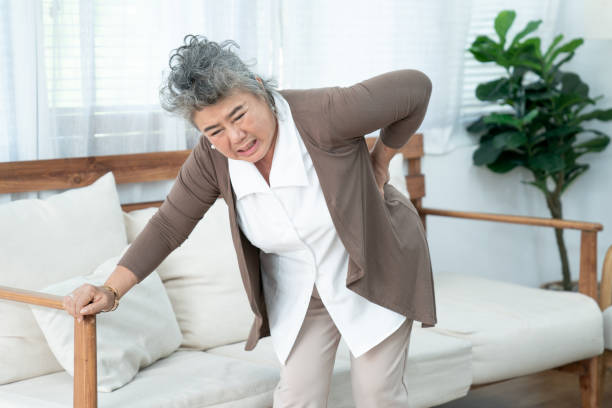 Senior Asian woman suffering from backache at home. stock photo
