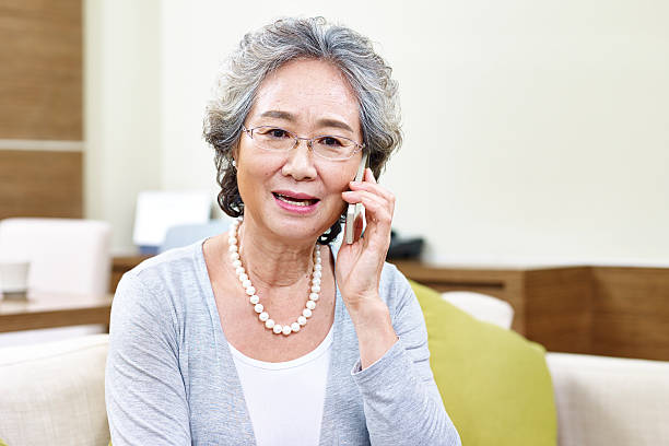 senior asian woman talking on cellphone senior asian woman talking on cellphone, appears to be disappointed, upset and unhappy asian woman using phone stock pictures, royalty-free photos & images