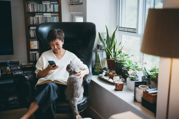 Senior Asian woman using a smartphone Senior Asian woman using smartphone to communicate with her friends at home , asian woman using phone stock pictures, royalty-free photos & images