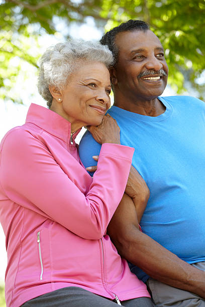 Senior black couple smiling at the park Portrait Of Senior African American Couple Wearing Running Clothing In Park old black couple in love stock pictures, royalty-free photos & images