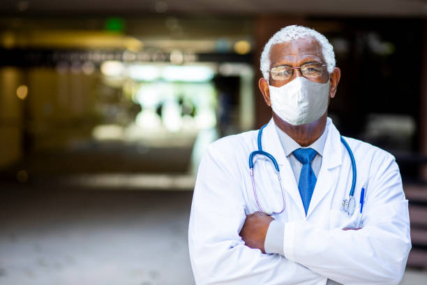 Senior Black Male Doctor Portrait at Hospital wearing mask Portrait of a senior African American doctor at the hospital wearing a mask sad old black man stock pictures, royalty-free photos & images