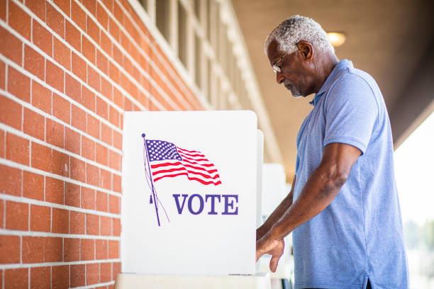 Senior Black Man Voting at Booth A senior black man voting at a voting booth presidential election stock pictures, royalty-free photos & images