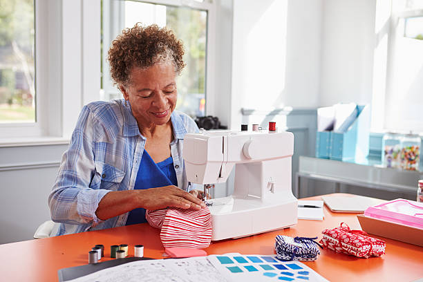 Senior black woman stitching fabric using a sewing machine Senior black woman stitching fabric using a sewing machine hobbies stock pictures, royalty-free photos & images