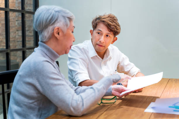 Senior business team leader is guiding young member to business success by showing chart for goal achievement for startup and creativity project concept stock photo