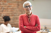 Senior Businesswoman In Office. Pretty older business woman, successful confidence with arms crossed in financial building. Cheerful attractive businesswoman crossing arms on chest and looking at camera.