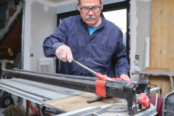 Senior contractor cutting a ceramic wood effect tile with a manual tile cutter. stock photo