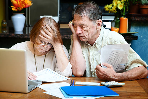 senior couple at home with many bills - geldstress stockfoto's en -beelden