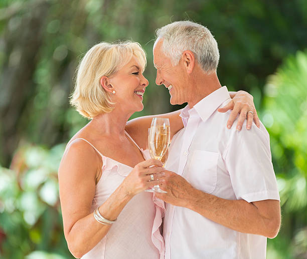 Senior Couple Celebrating A Senior Couple Celebrating With Champagne wedding anniversary stock pictures, royalty-free photos & images