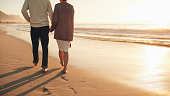 istock Senior couple holding hands walking on the beach 629225214