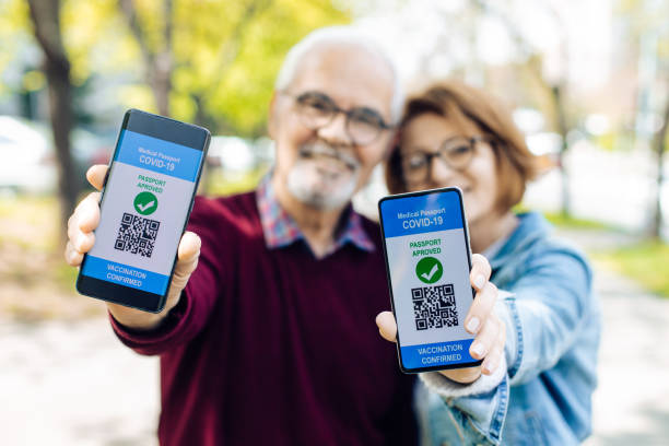 Senior couple showing smartphones with electronic vaccination certificates stock photo