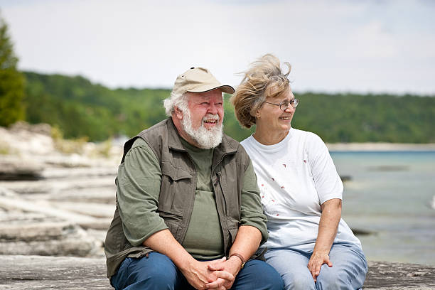 Senior couple sitting at shores edge stock photo