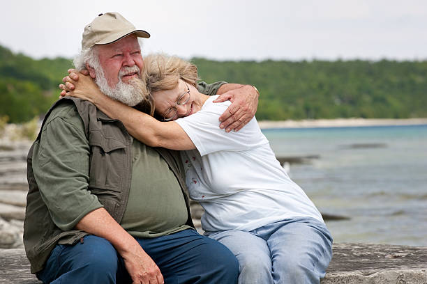 Senior couple sitting at shores edge stock photo