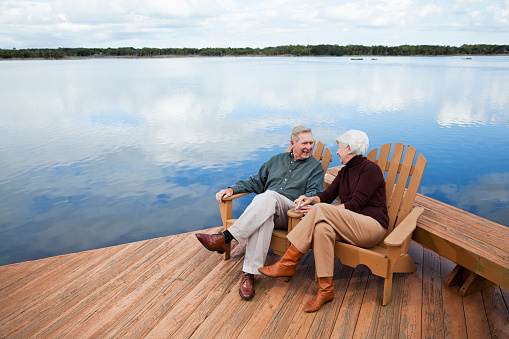 Senior couple (60s) sitting on wooden deck with water view.   Intracoastal Waterway, Florida.
