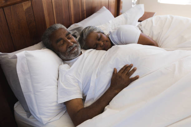 senior couple sleeping together in bedroom - sleeping couple imagens e fotografias de stock