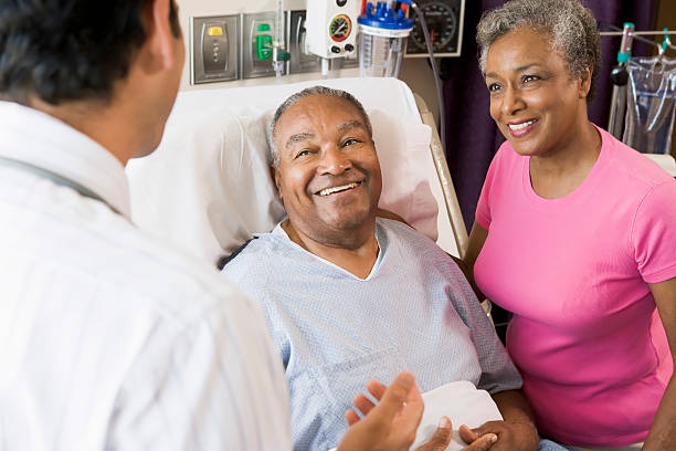 Senior Couple Talking with doctor Senior Couple Talking,With Doctor smiling patient in hospital bed stock pictures, royalty-free photos & images