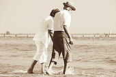 Senior couple walking on the beach. Sepia toned image.