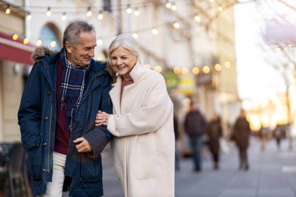 senior paar wandelen op de straat van de stad op de winterdag - happy couple cold stockfoto's en -beelden