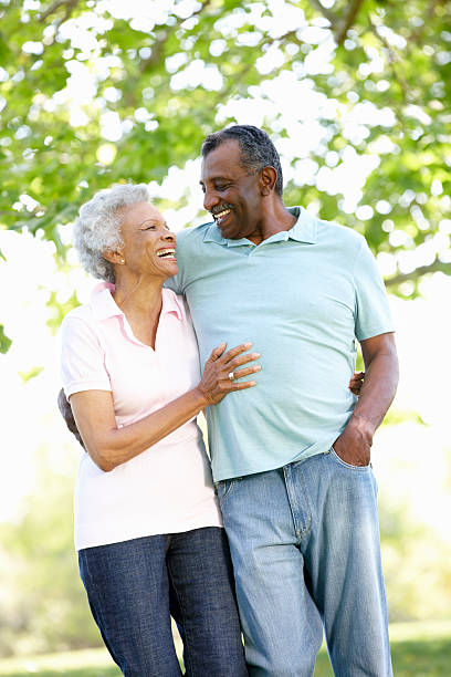 Senior couple walking through park on a sunny day Romantic Senior African American Couple Walking In Park And Laughing old black couple in love stock pictures, royalty-free photos & images