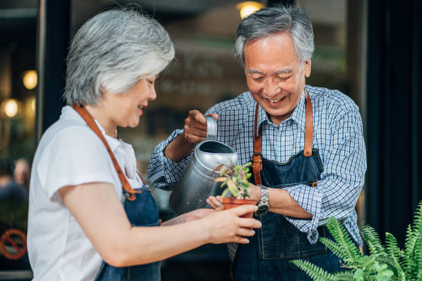Senior couple watering plants together Man and woman, senior Taiwanese couple watering plants together. couple gardening stock pictures, royalty-free photos & images
