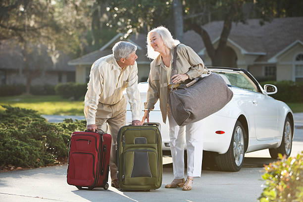 senior couple with suitcases and convertible - house with 2 cars bildbanksfoton och bilder